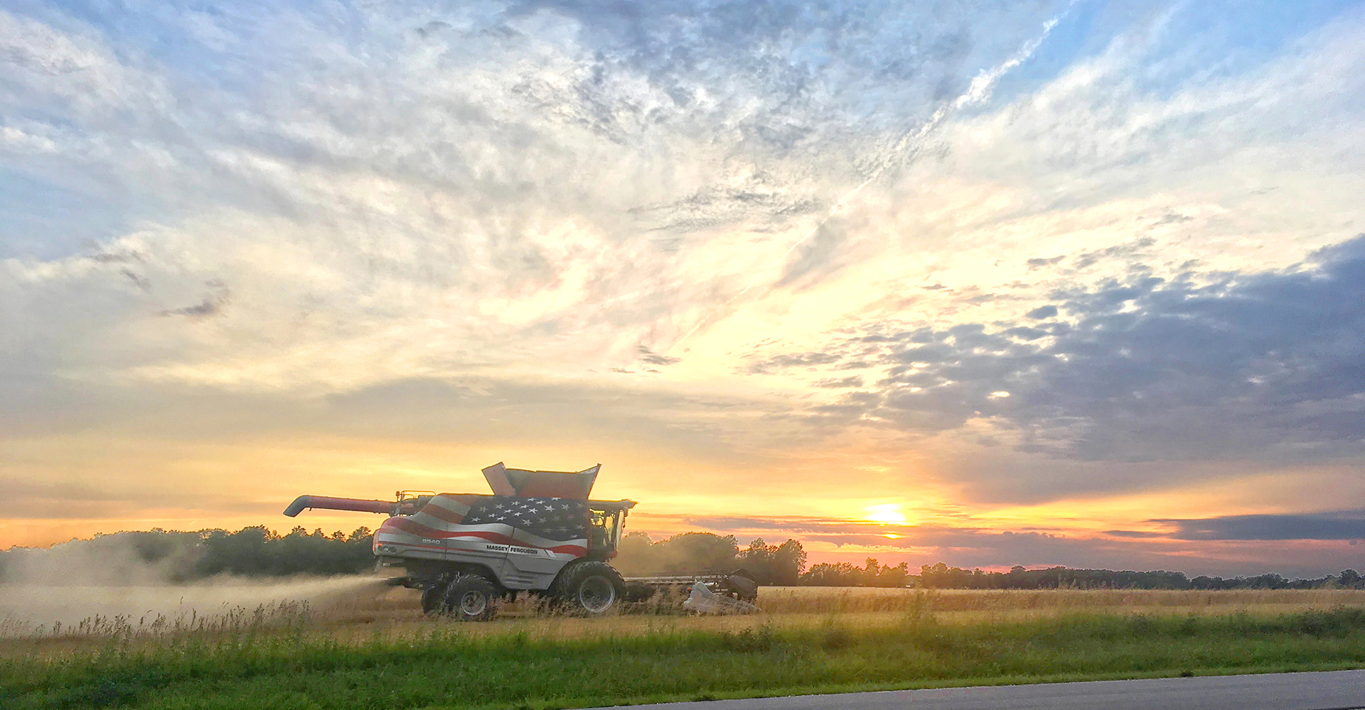 Combine in field, farming, sunset